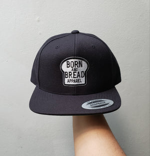 Snapback Hat with a larger Born and Bread Apparel logo in the front